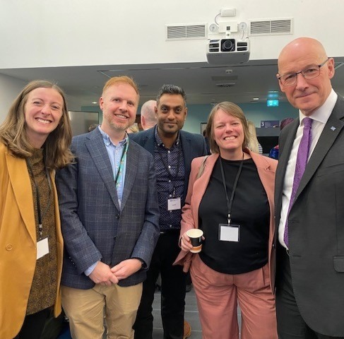 A photograph of five people. From left to right: Sara Redmond (The Alliance), Nick Ward (Change Mental Health), Tejesh Mistry (Voluntary Health Scotland), Rachel Cackett (CCPS) and John Swinney (First Minister).